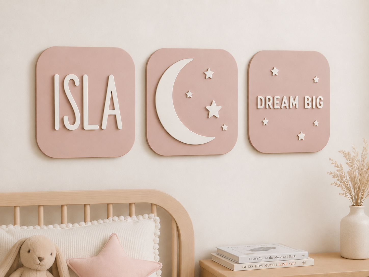 Nursery wall art in pink with a name sign, a moon with stars and a motivational "dream big" message with small stars